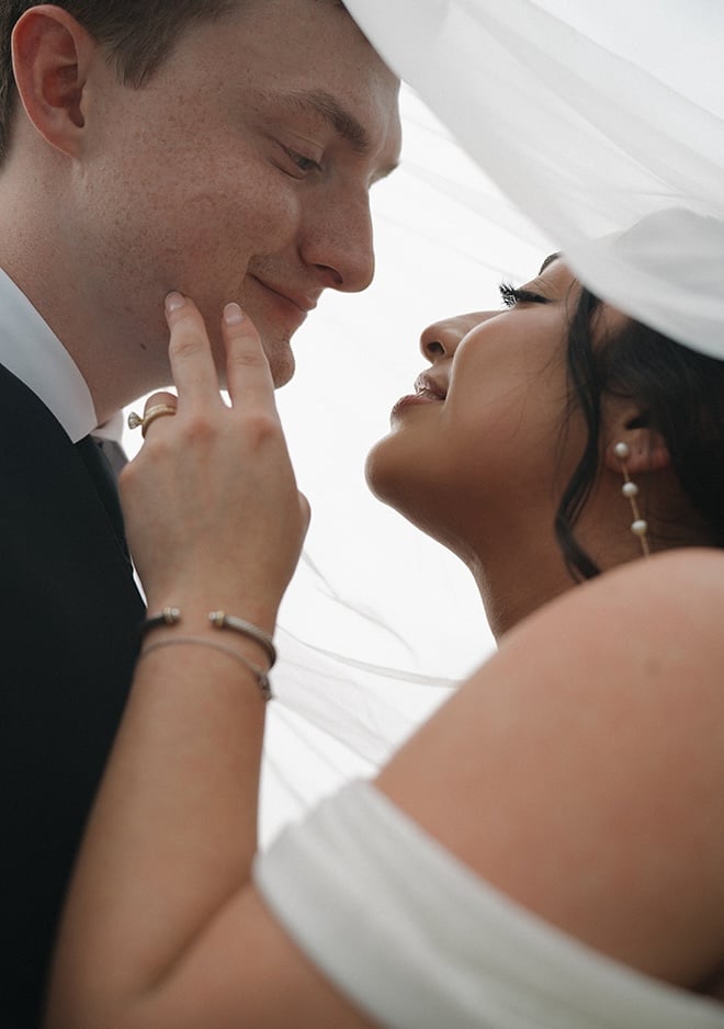 Mandi Roach Photography captures the bride and groom under the wedding veil. 