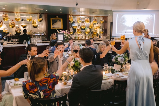 Guests clinking glasses sitting at a table at Ouisie's Table. 