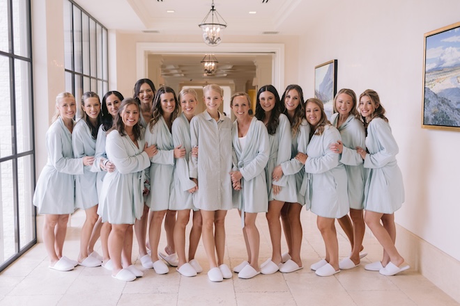 The bride and her bridesmaids smiling together wearing blue pajamas. 