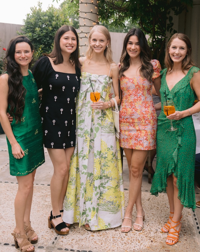 The bride wearing a green and yellow long dress posing with four other ladies. 