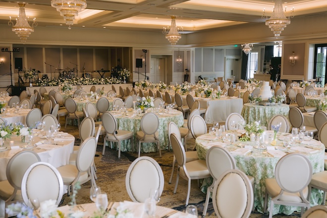 The reception space decorated in green linens, florals and neutral chairs. 