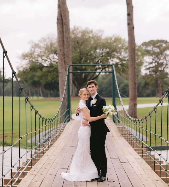 A bride and groom smiling on the bridge of Lakeside Country Club. 