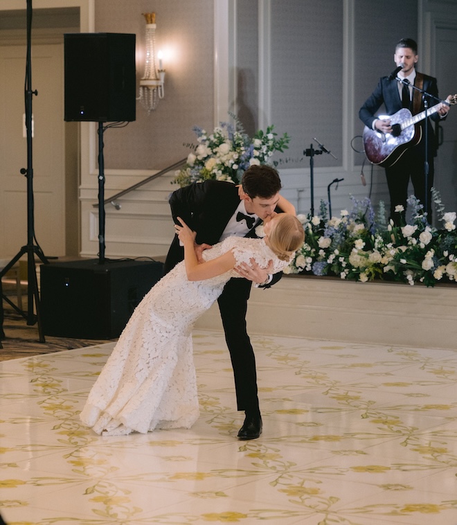 The groom dipping the bride and kissing her during the first dance on the yellow floral print dance floor. 