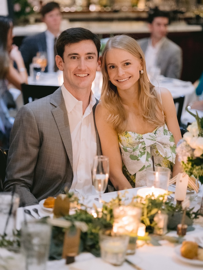 The bride and groom sitting at a table at Ouisie's Table during their rehearsal dinner. 