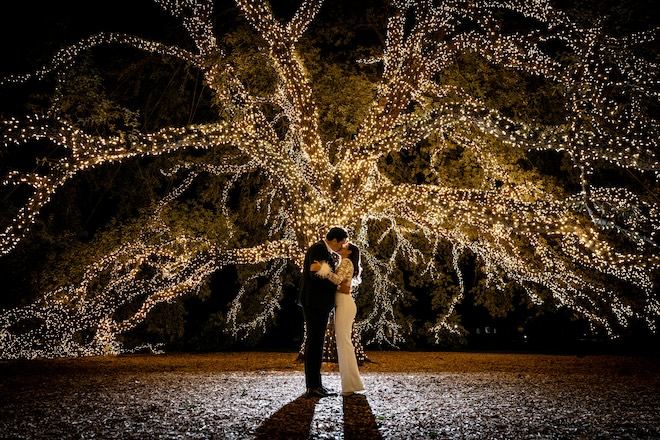 The bride and groom kissing under the lit up oak tree at The Houstonian Hotel, Club & Spa. 