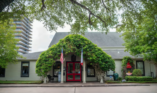 The exterior of Ouisie's Table- a green wood building with a red door. 