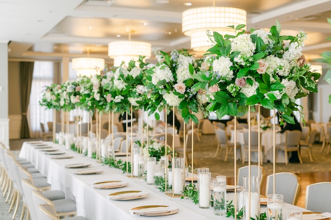 A reception table decorated with tall floral centerpieces in the ballroom at the Tremont House. 