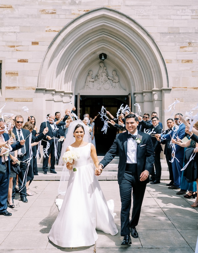 Wedding guests cheer for the newlyweds as they exit their wedding ceremony in Houston. 