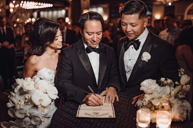 The officiant signs the bride and grooms marriage license at their wedding reception.