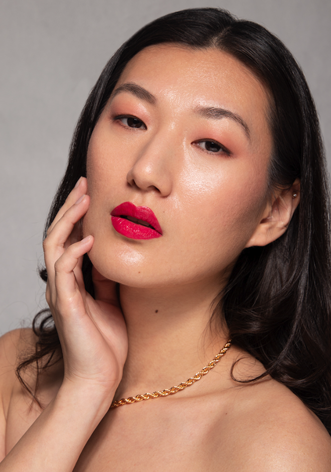 The model wears a bold red lip with a soft pink eyeshadow. 