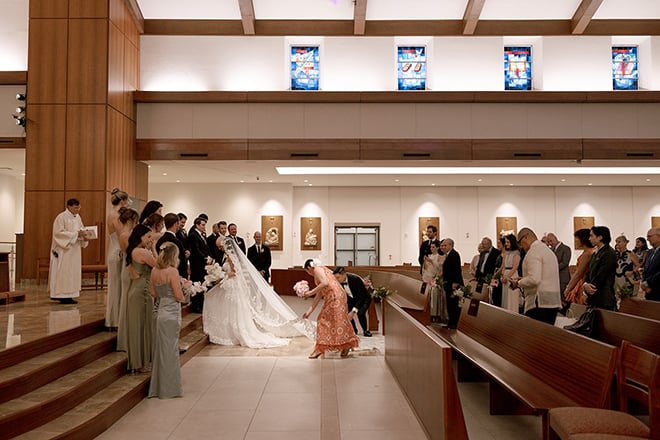 The mother of the bride and her brother fix her veil at the altar. 