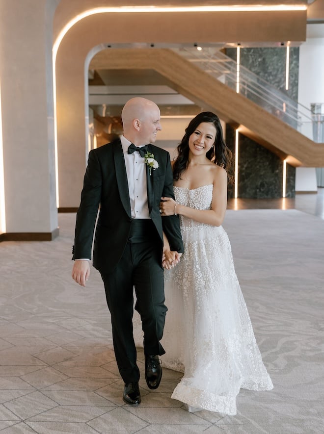 The bride and groom hold hands as they walk around the Thompson Houston, by Hyatt. 