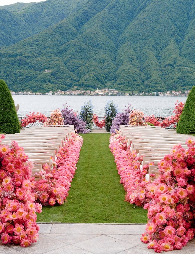 Pink, lavender, blue and peach flowers decorate the outdoor wedding ceremony. 