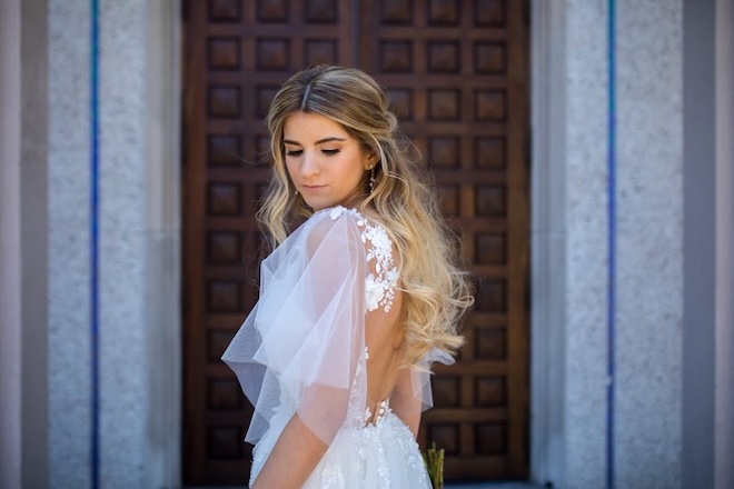 A bride wearing a tulle and lace wedding gown with her hair half up half down and a bridal spray tan. 