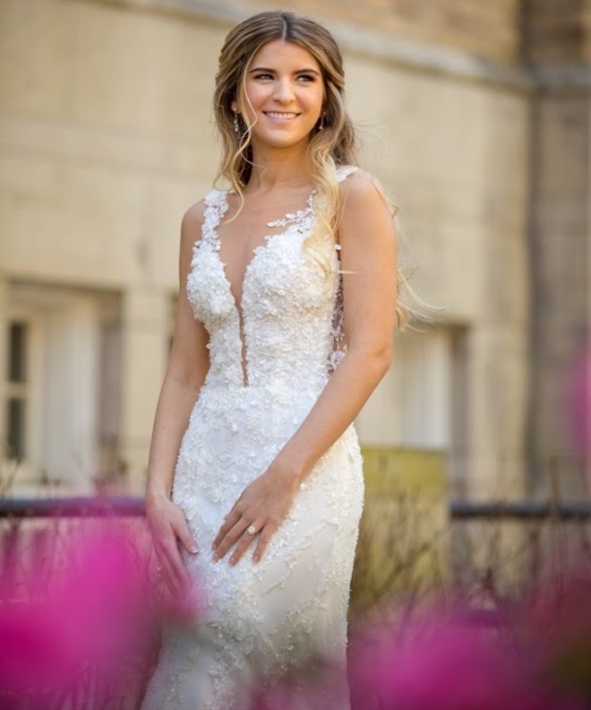 A bride smiling in a wedding gown and a Honey Hue spray tan. 