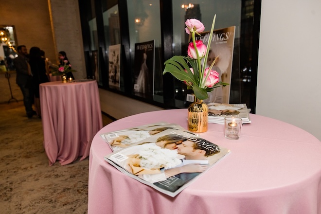 Pink linens on round tables decorated with magazines and florals. 