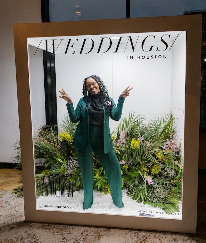 A woman in the life-size magazine cover photo booth doing peace signs. 