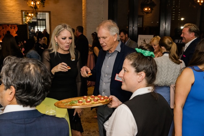 Guests taking light bites from a tray. 