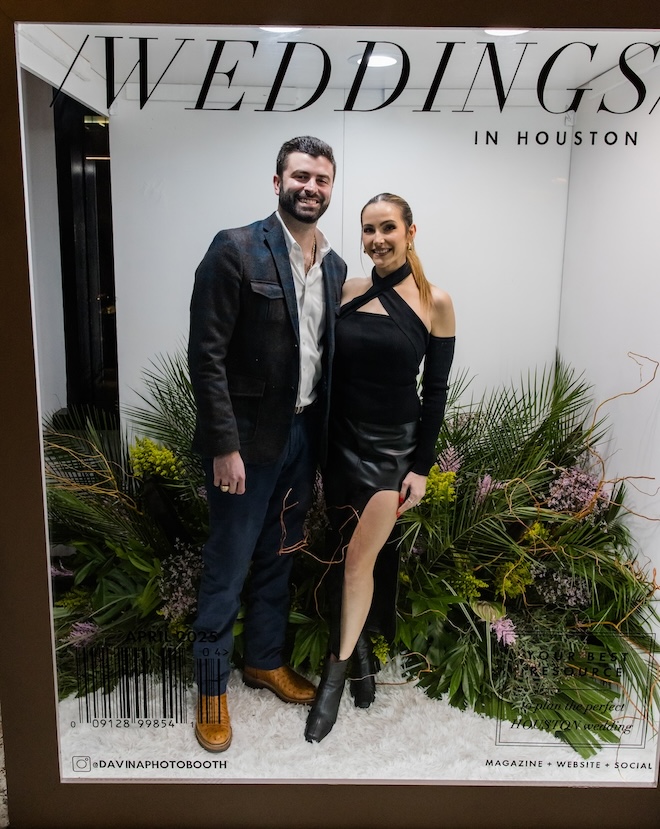 A couple posing in the life-size magazine cover photobooth. 