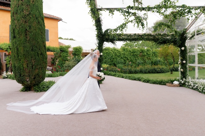 The bride and her father walk down the aisle at their wedding ceremony in Venice, Italy. 